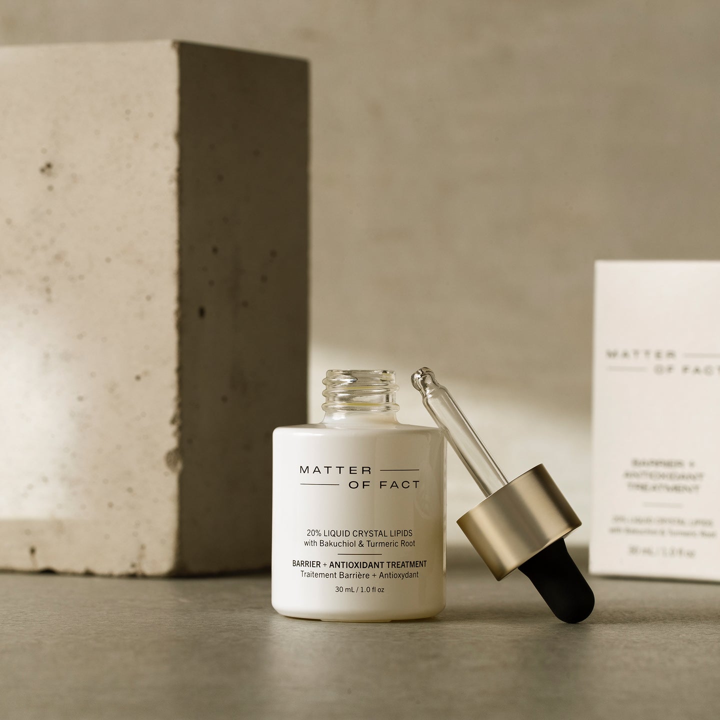 MATTER OF FACT SKINCARE BARRIER AND ANTIOXIDANT TREATMENT product vessel on a beige background with the product packaging and applicator visible