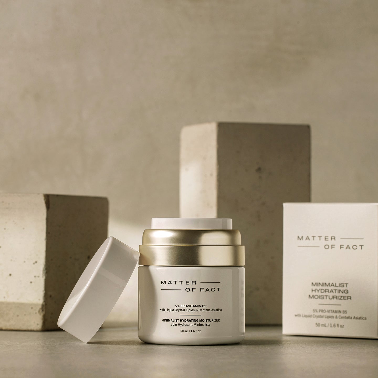 MATTER OF FACT SKINCARE MINIMALIST HYDRATING MOISTURIZER product vessel on a beige background with the product packaging and applicator visible