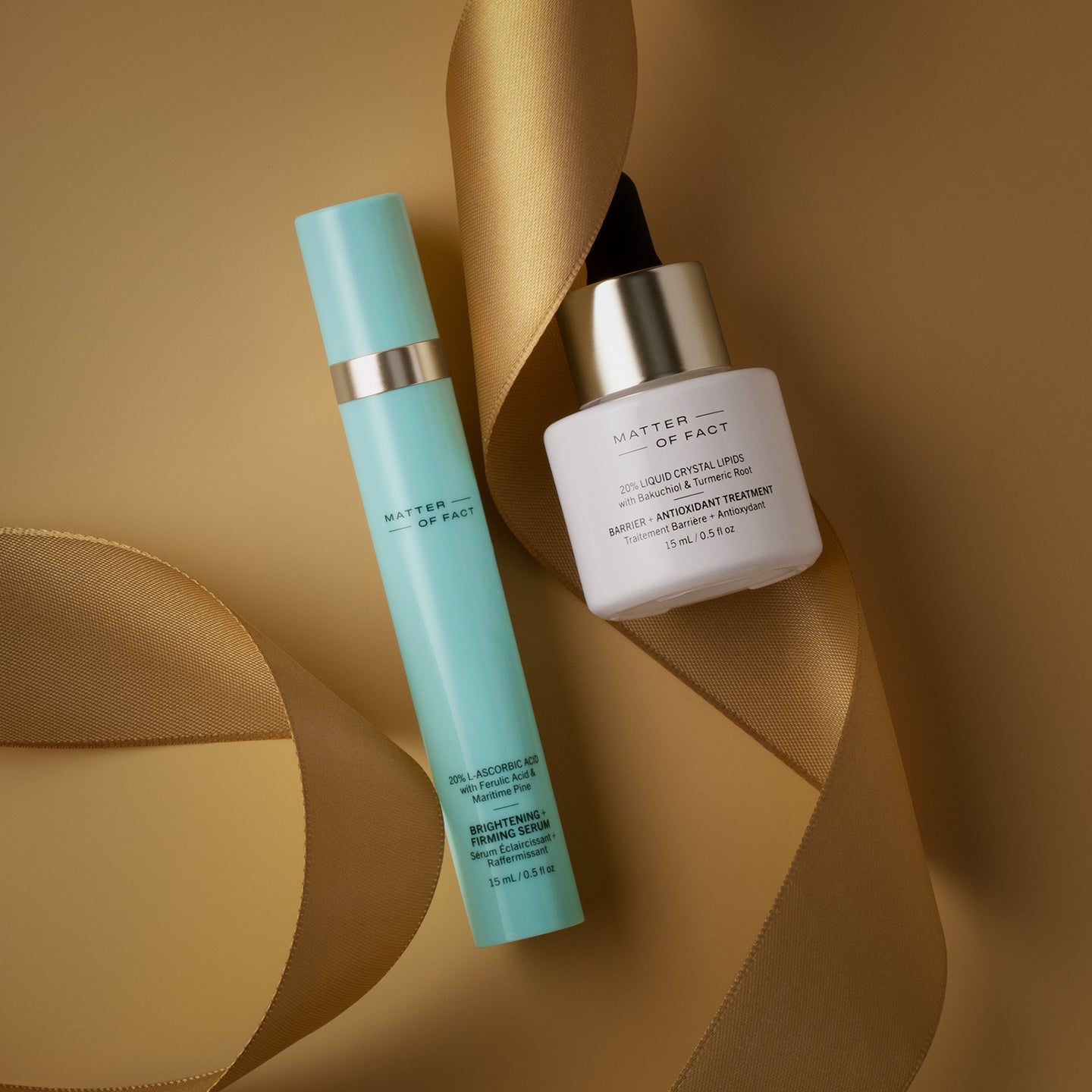 BRIGHTENING + FIRMING SERUM travel size and BARRIER + ANTIOXIDANT TREATMENT travel size on gold background with ribbon