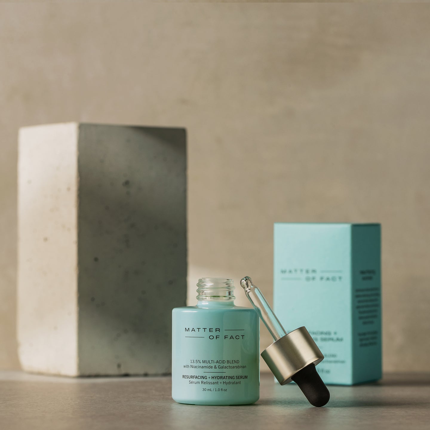 MATTER OF FACT SKINCARE RESURFACING AND HYDRATING SERUM product vessel on a beige background with the product packaging and applicator visible